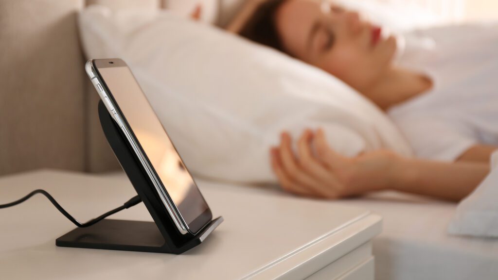woman sleeping in bed with smart phone charging on her night stand