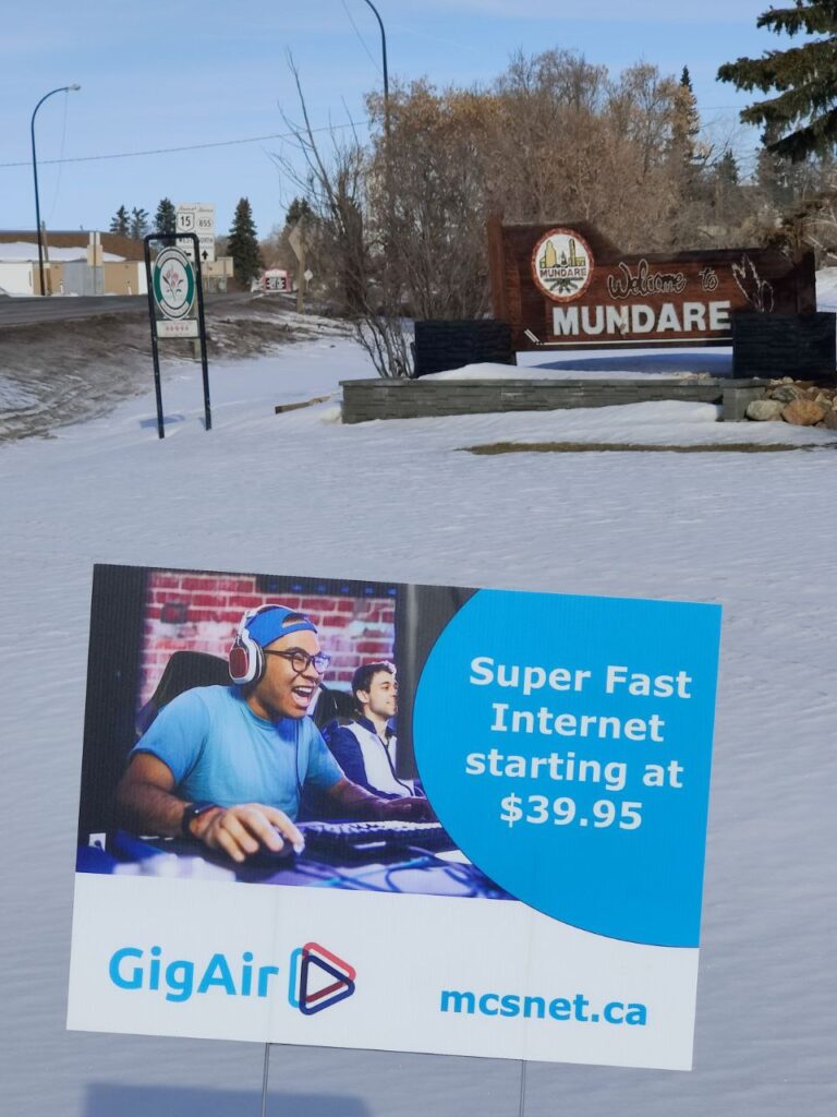 Picture of GigAir lawn sign in front of Welcome to Mundare sign.