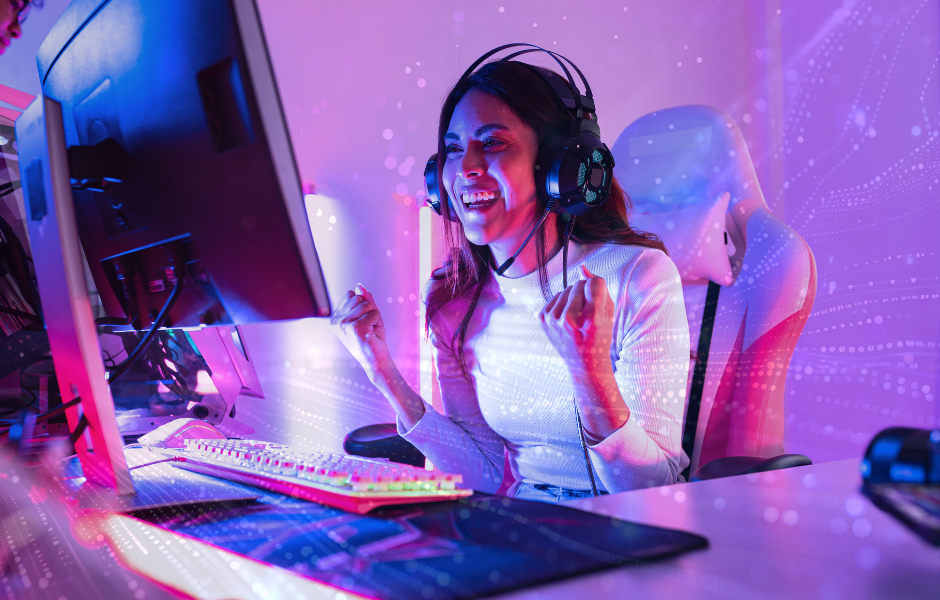 Image of a woman sitting in front of a gaming computer, wearing headphone, and cheering.