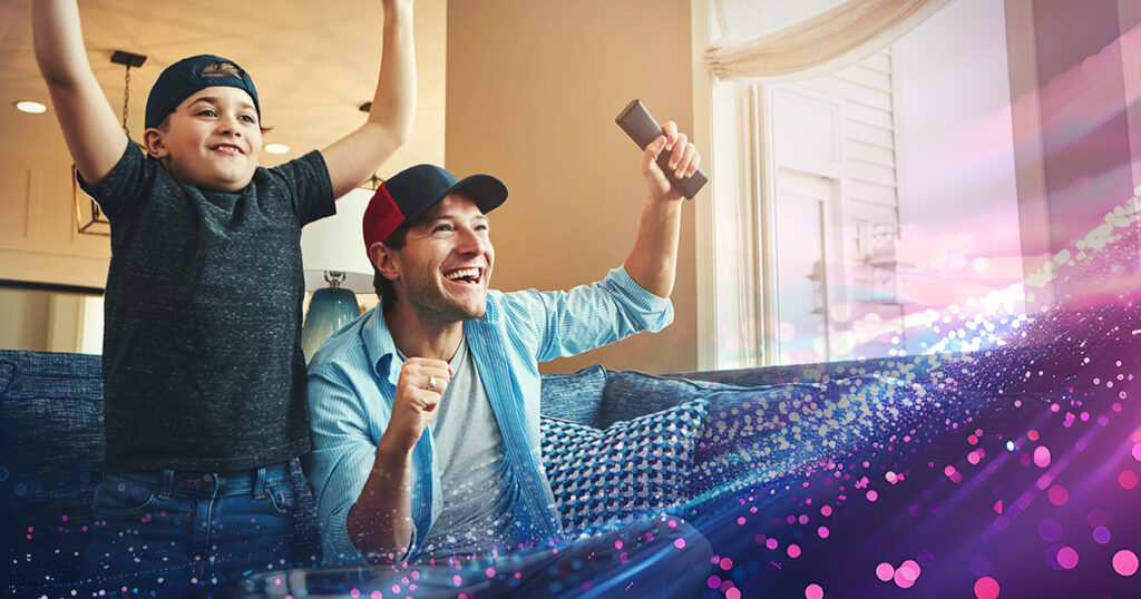 Father and son cheering on their favourite sports team on TV.