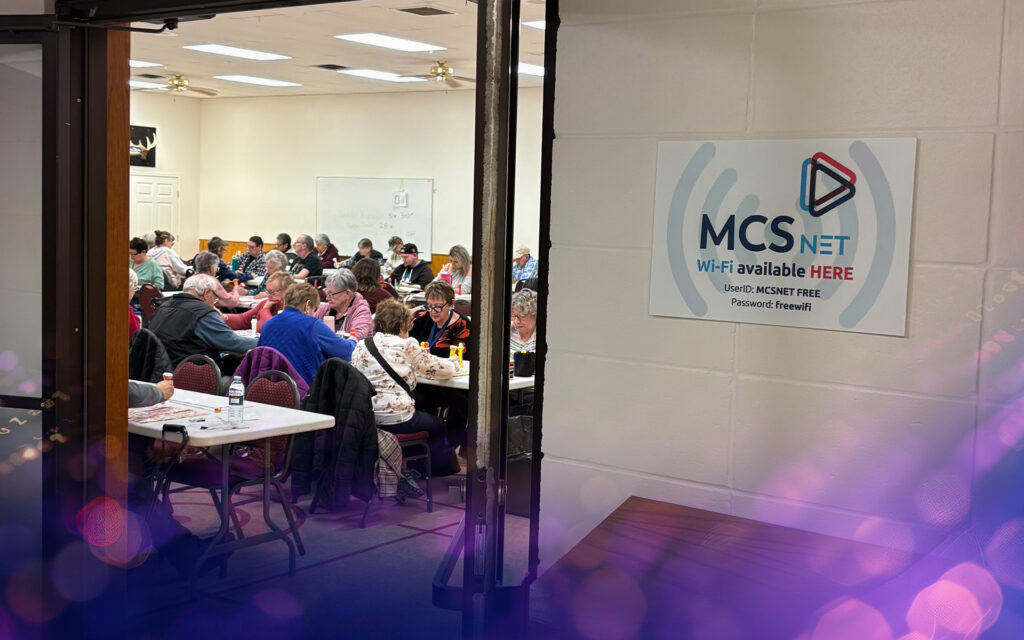 A picture of seniors playing bingo at the Pioneer Circle Centre with the MCSnet Free Wi-fi sign in the foreground.