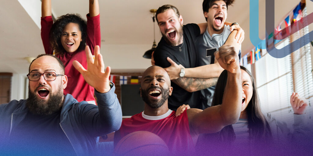 A group of young adults sitting in front of a TV and cheering.