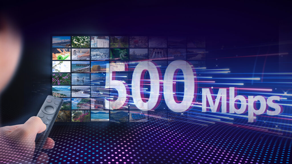 Graphic image of a multiple screens in a grid pattern in the background with the words, 500 Mbps, splashed across the image. A close-up view of a hand holding a remote is in the foreground.