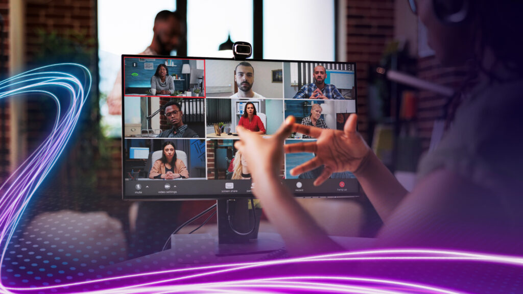 Back and side view of a person speaking during a video conference meeting with attendees faces presented on the screen.