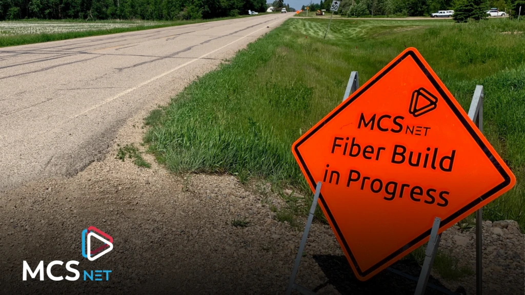 Image of an orange, diamond-shaped road sign that states: MCSnet Fiber Build in Progress.