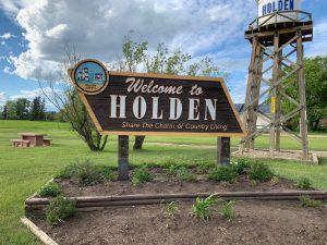 Welcome to Holden sign with the village's wooden water tower in the background