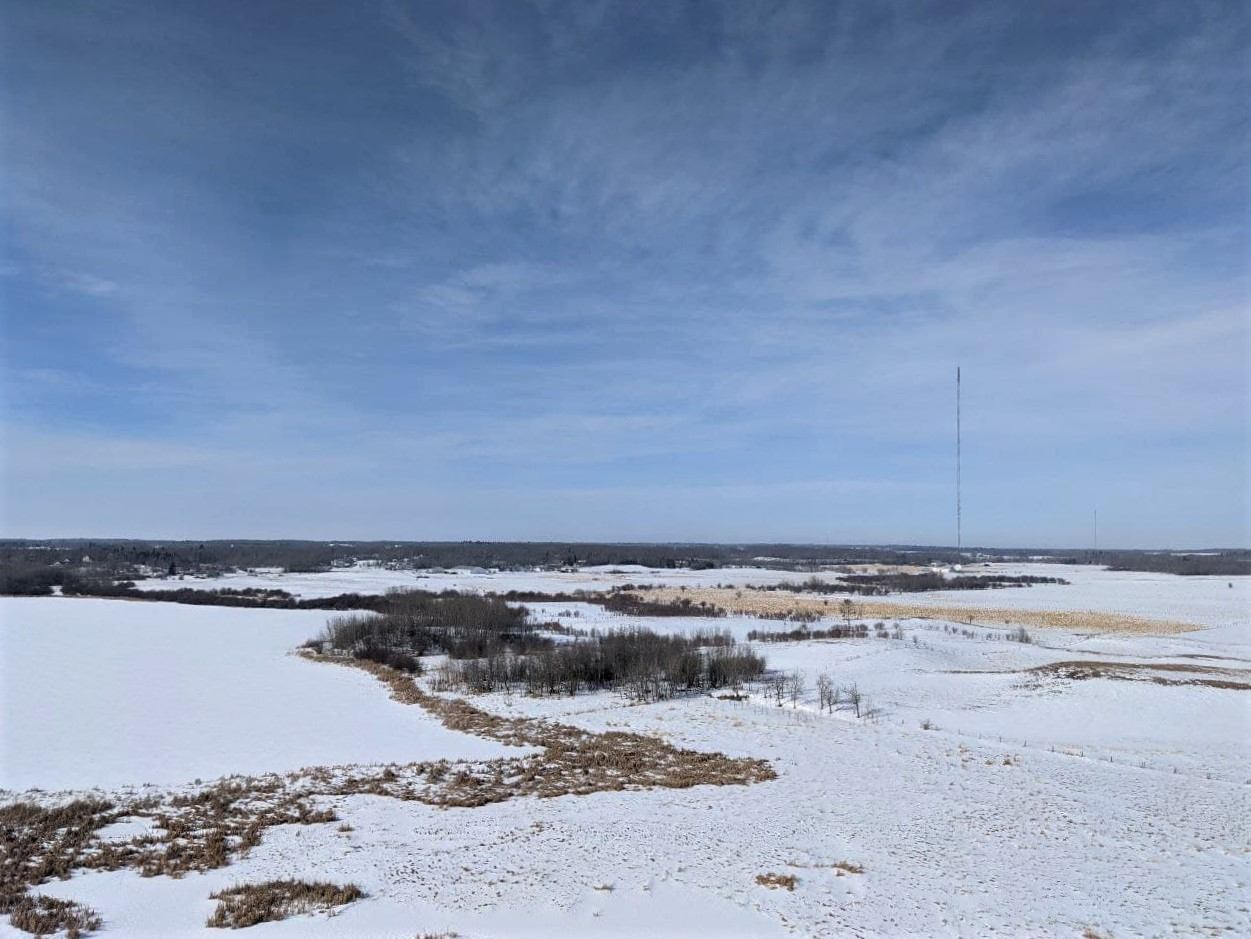 Snow covered farmland near Looma, Alberta with a distant communications tower on the horizon