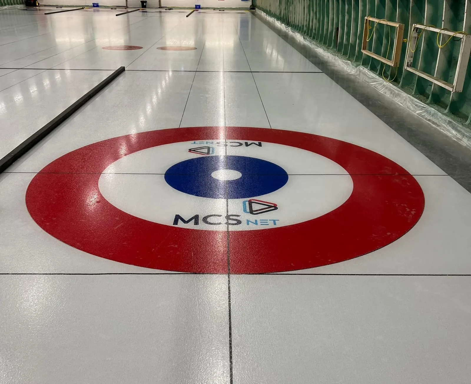 Curling ice at the Elk Point and District Curling Society rink in Elk Point, Alberta, with the MCSnet logo painted inside the house