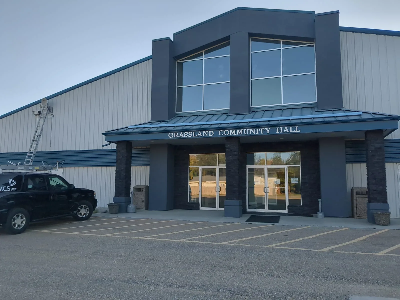 Exterior of the Grassland Community Hall in Grassland, Alberta, with an MCSnet service truck and ladder parked out front