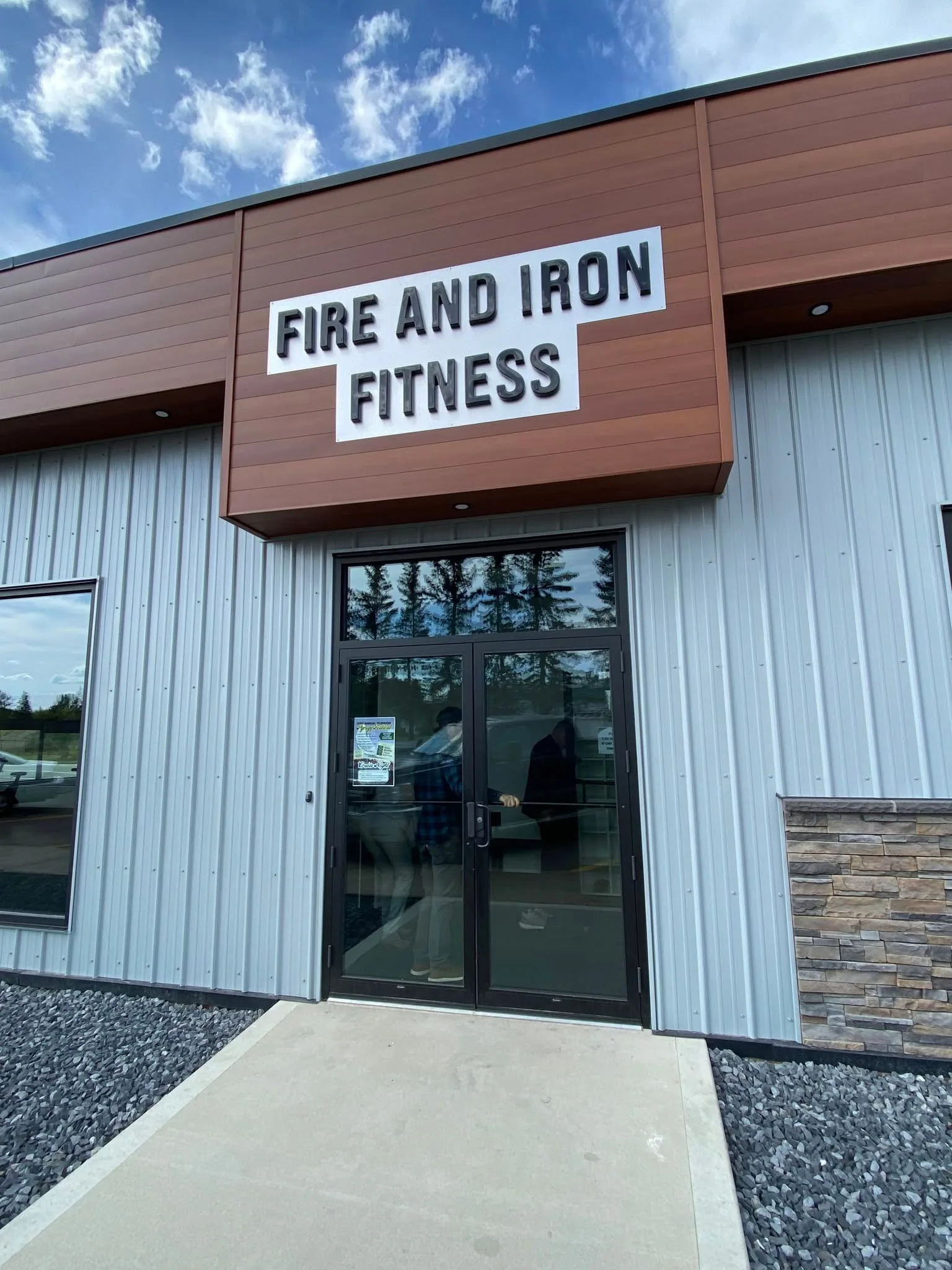 Exterior entrance of the Village of Glendon's community gym, with the Fire and Iron Fitness sign above the glass doors